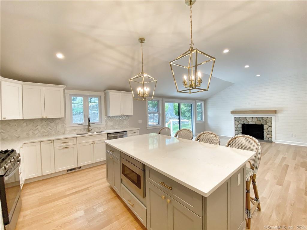 a open kitchen with stainless steel appliances granite countertop a sink a stove a dining table and chairs