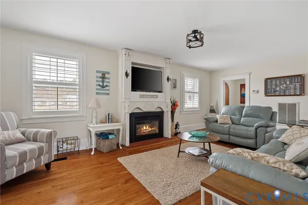 a living room with furniture a fireplace a flat screen tv and a large window