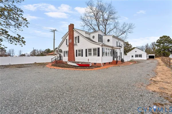 a view of a white house with a big yard and large trees