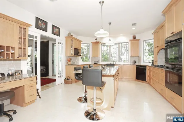 a kitchen with stainless steel appliances kitchen island granite countertop a refrigerator a stove a sink dishwasher and a dining table with the kitchen view