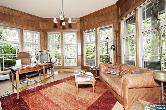 a living room with furniture large windows and wooden floor