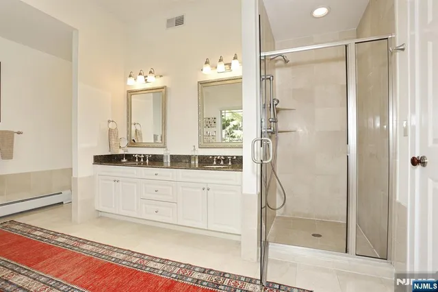 a bathroom with a double vanity sink mirror and shower