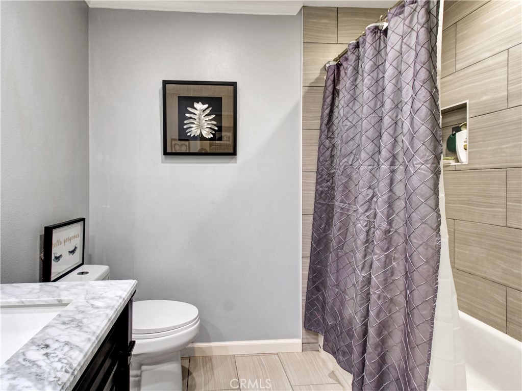 1669 Erin Avenue Upland, CA 91784 - Photo 14 of 27 a bathroom with a granite countertop toilet and a shower