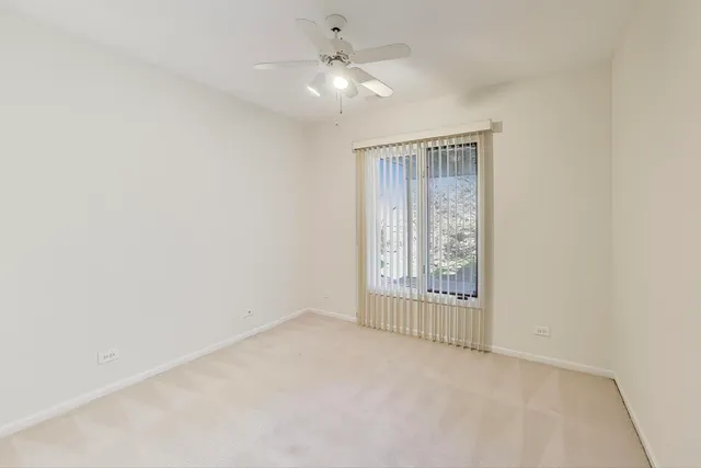 an empty room with chandelier fan and windows