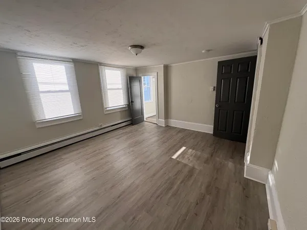 an empty room with wooden floor and windows