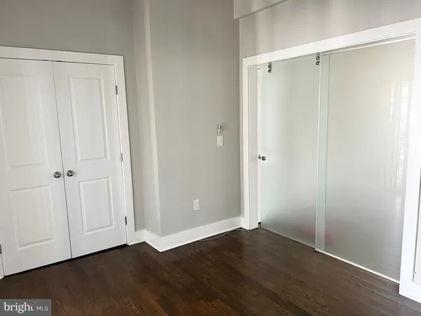 a view of an empty room with wooden floor and closet area