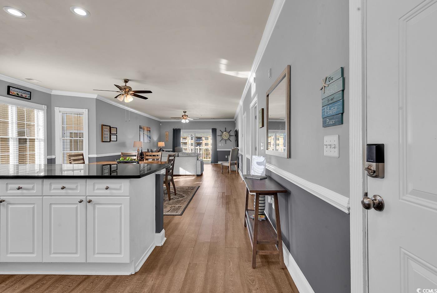 4829 Luster Leaf Circle, Unit 301 Myrtle Beach, SC 29577 - Photo 34 of 34 Kitchen featuring ornamental molding, open floor plan, white cabinets, dark wood-style flooring, and dark stone countertops