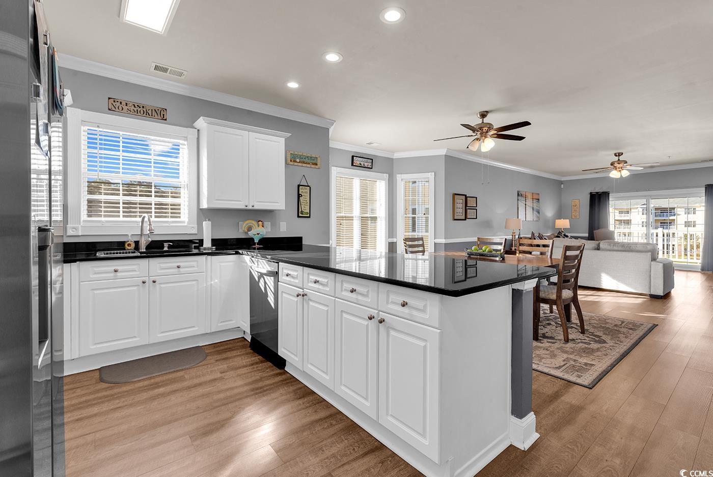 4829 Luster Leaf Circle, Unit 301 Myrtle Beach, SC 29577 - Photo 33 of 34 Kitchen with white cabinetry, crown molding, open floor plan, light wood-type flooring, and a peninsula