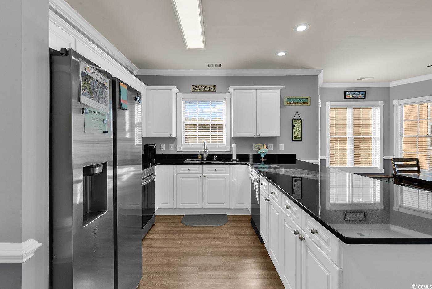 4829 Luster Leaf Circle, Unit 301 Myrtle Beach, SC 29577 - Photo 7 of 34 Kitchen with crown molding, appliances with stainless steel finishes, white cabinets, dark stone countertops, and light wood-style floors