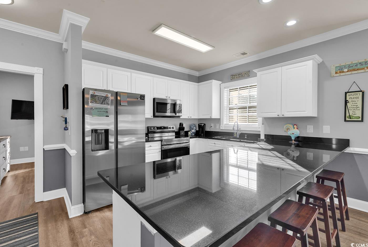 4829 Luster Leaf Circle, Unit 301 Myrtle Beach, SC 29577 - Photo 8 of 34 Kitchen featuring a kitchen bar, stainless steel appliances, white cabinets, ornamental molding, and recessed lighting