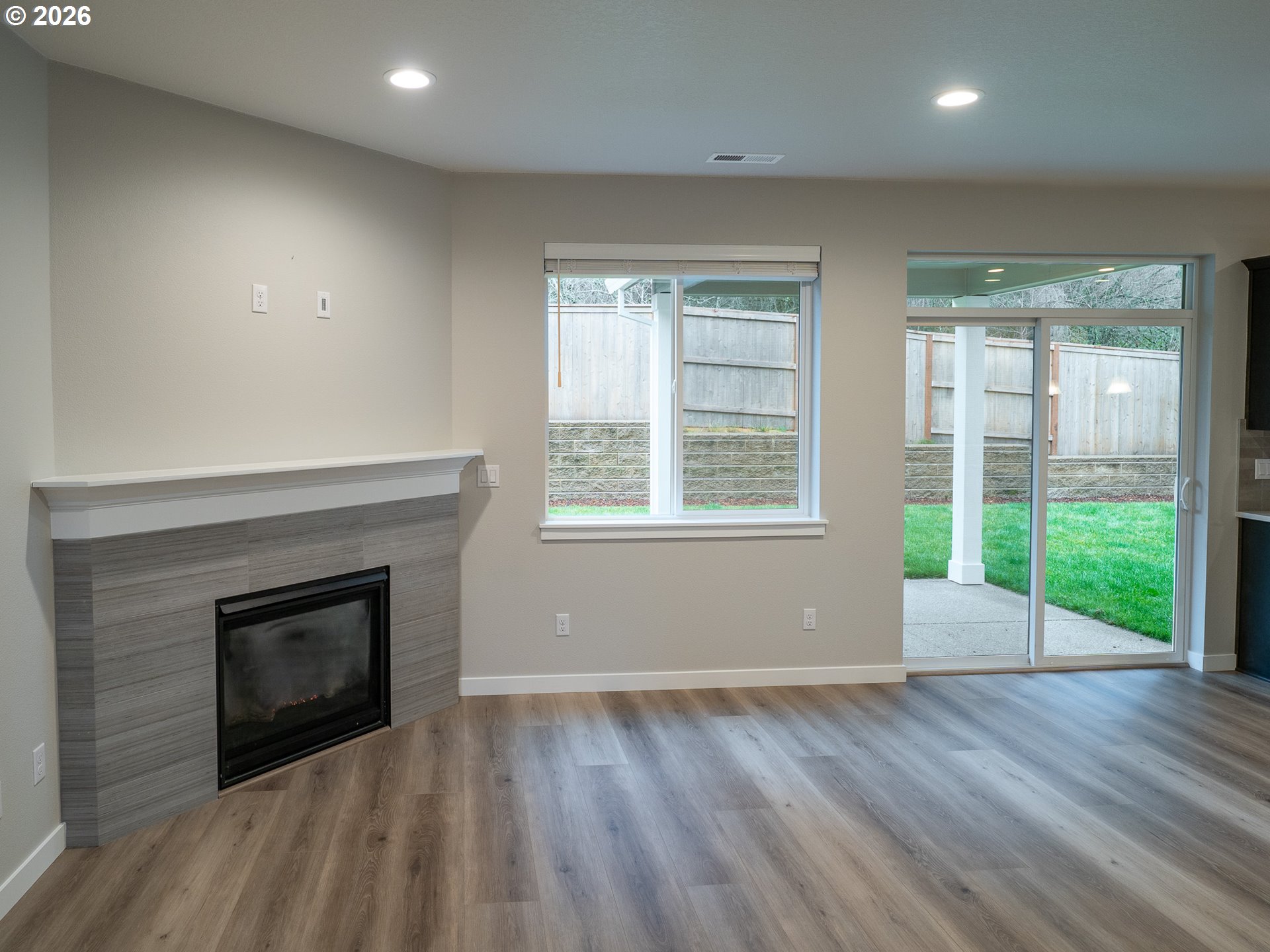 10495 Southeast Heritage Road Happy Valley, OR 97086 - Photo 6 of 46 an empty room with wooden floor fireplace and windows