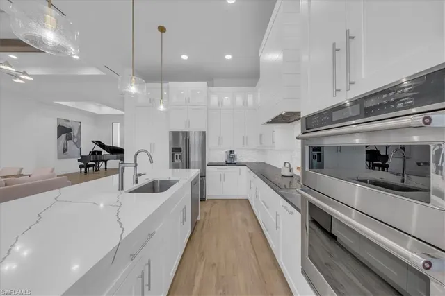 a large white kitchen with stainless steel appliances
