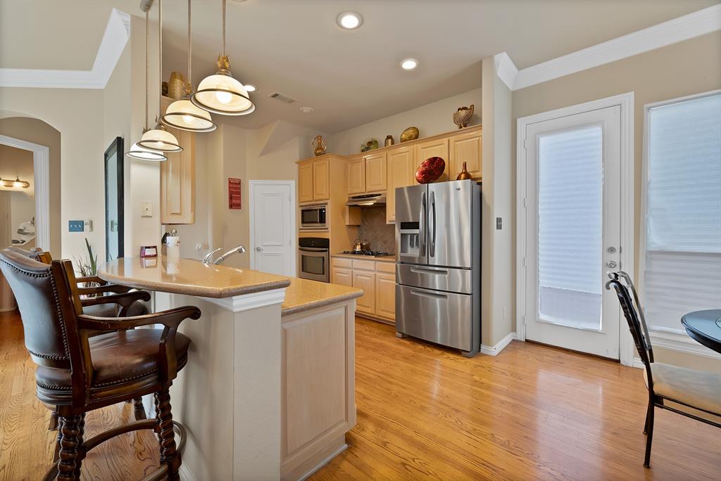 1014 Ricci Court Irving, TX 75062 - Photo 11 of 30 Kitchen featuring crown molding, appliances with stainless steel finishes, hanging light fixtures, a peninsula, and tasteful backsplash