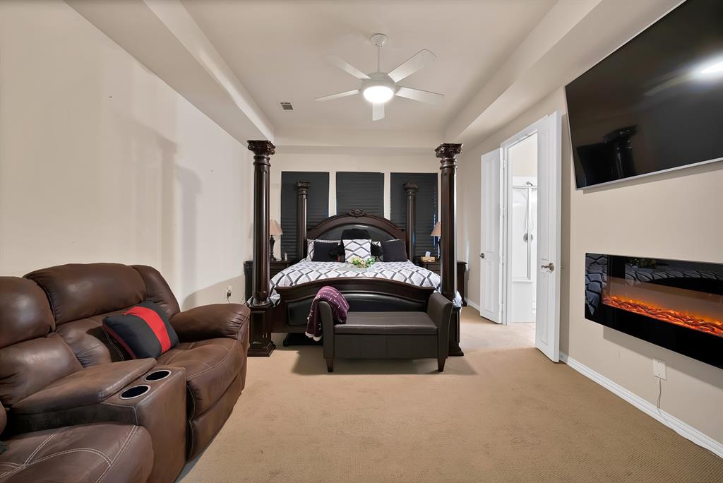 1014 Ricci Court Irving, TX 75062 - Photo 14 of 30 Bedroom featuring carpet, a glass covered fireplace, ceiling fan, and a raised ceiling