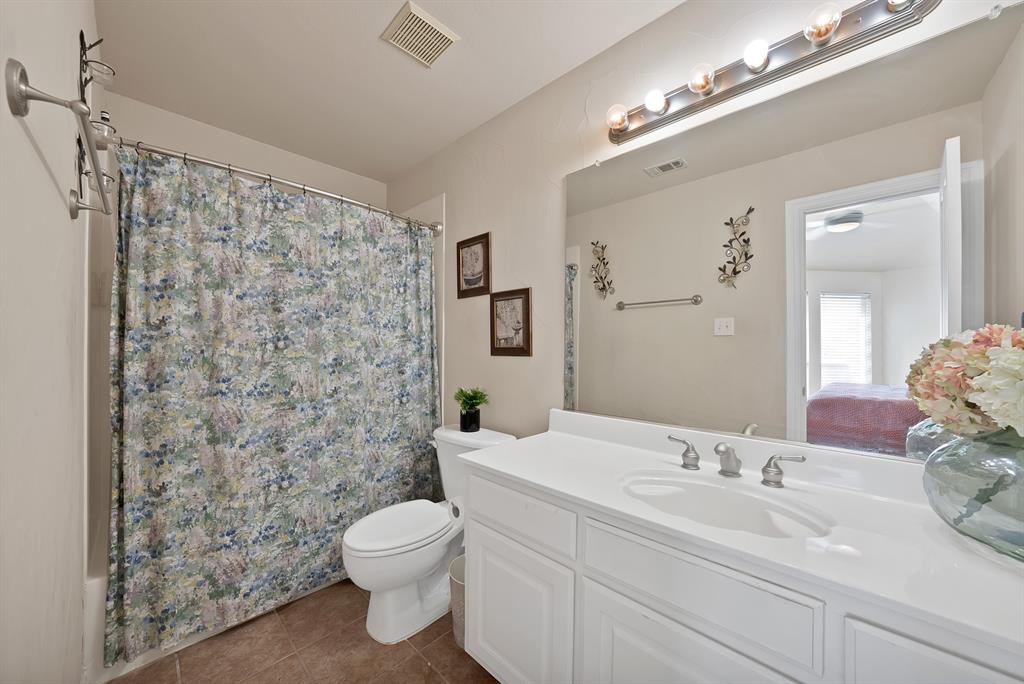 1014 Ricci Court Irving, TX 75062 - Photo 25 of 30 Ensuite bathroom featuring vanity, dark tile patterned floors, and shower / tub combo with curtain