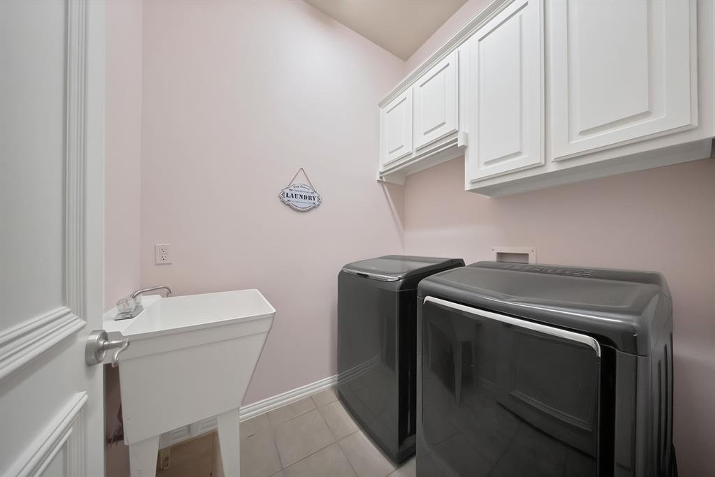 1014 Ricci Court Irving, TX 75062 - Photo 27 of 30 Laundry area featuring light tile patterned floors, cabinet space, and washing machine and clothes dryer