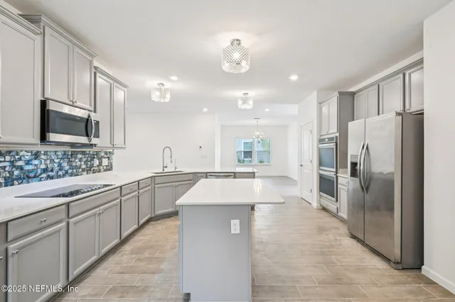 a large kitchen with cabinets a sink and stainless steel appliances