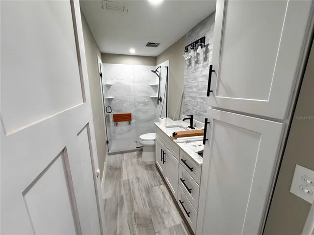 a bathroom with a granite countertop sink a mirror and a shower