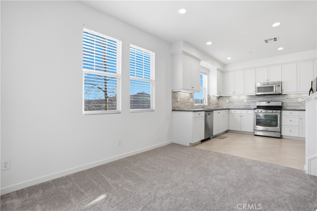 179 Patria Rancho Mission Viejo, CA 92694 - Photo 13 of 75 a kitchen with stainless steel appliances granite countertop a stove a sink a refrigerator white cabinets and a window
