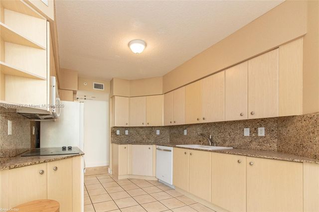 a kitchen with granite countertop a sink a stove and cabinets