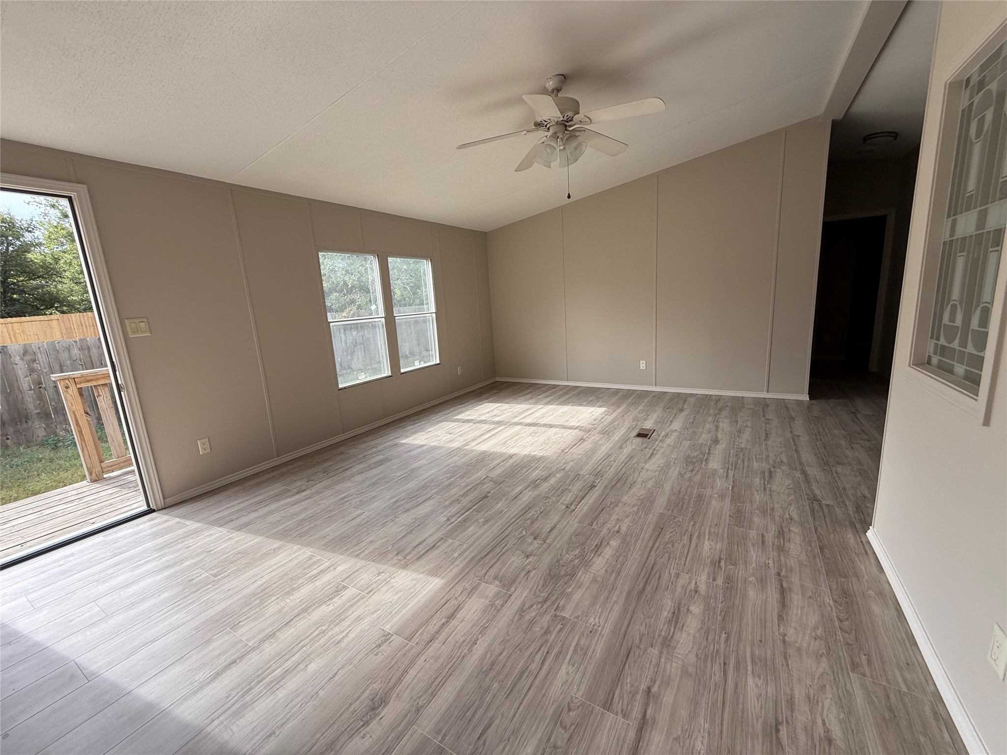 20701 Liveoak Lane Manor, TX 78653 - Photo 10 of 31 Unfurnished room with wood finished floors, vaulted ceiling, ceiling fan, and a decorative wall