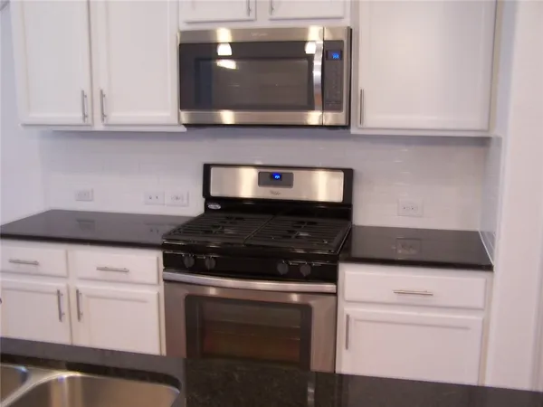 a kitchen with granite countertop white cabinets and stainless steel appliances