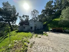 a front view of a house with a yard covered with trees