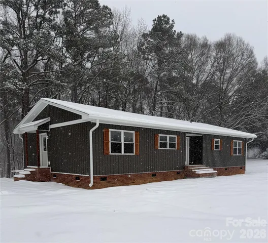 a view of house with outdoor space and trees in the background