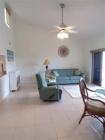a living room with couches a chandelier and a dining table with wooden floor