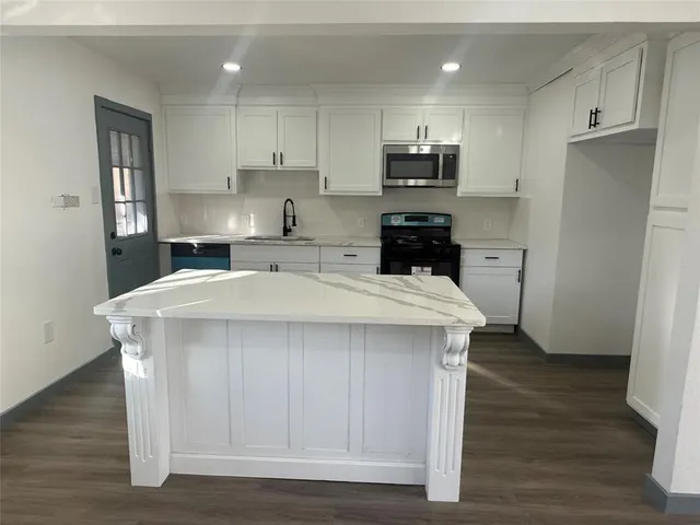 a kitchen with a sink a microwave a refrigerator and cabinets