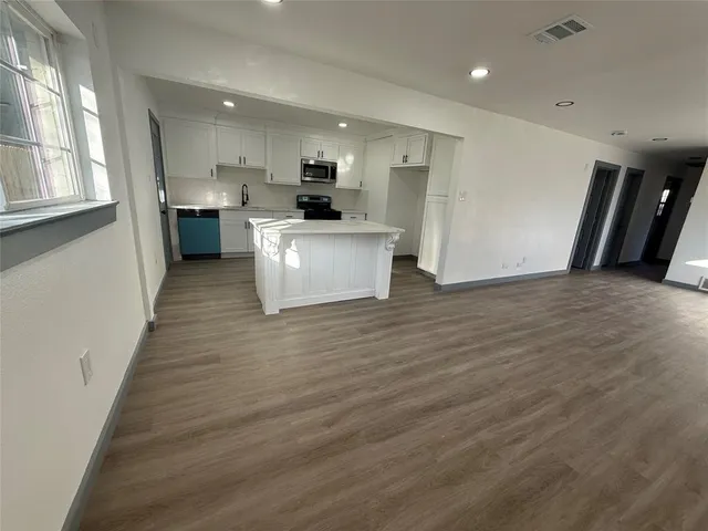 a view of kitchen with kitchen island wooden floors appliances and cabinets