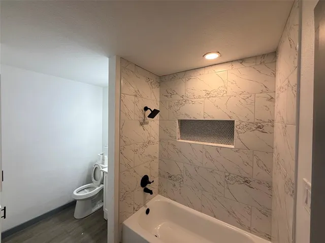 a bathroom with a granite countertop toilet a sink and shower