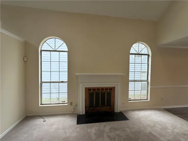 an empty room with windows fireplace and fans