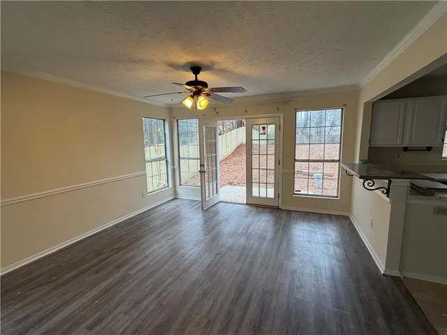 an empty room with wooden floor fan and windows