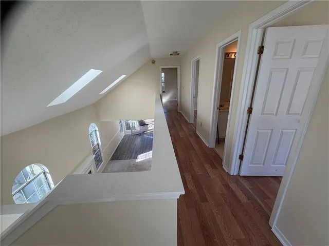 a view of a hallway to room with wooden floor