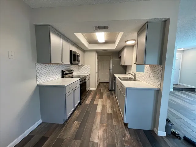 a large kitchen with a sink and dishwasher a stove top oven with wooden floor