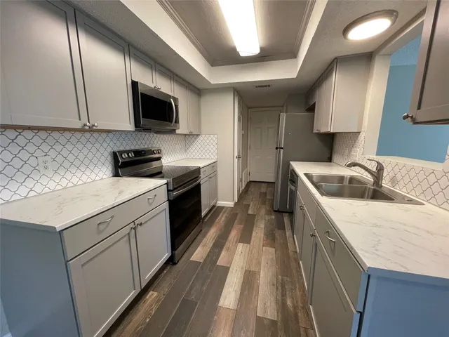 a kitchen with granite countertop a sink a counter top space stainless steel appliances and cabinets