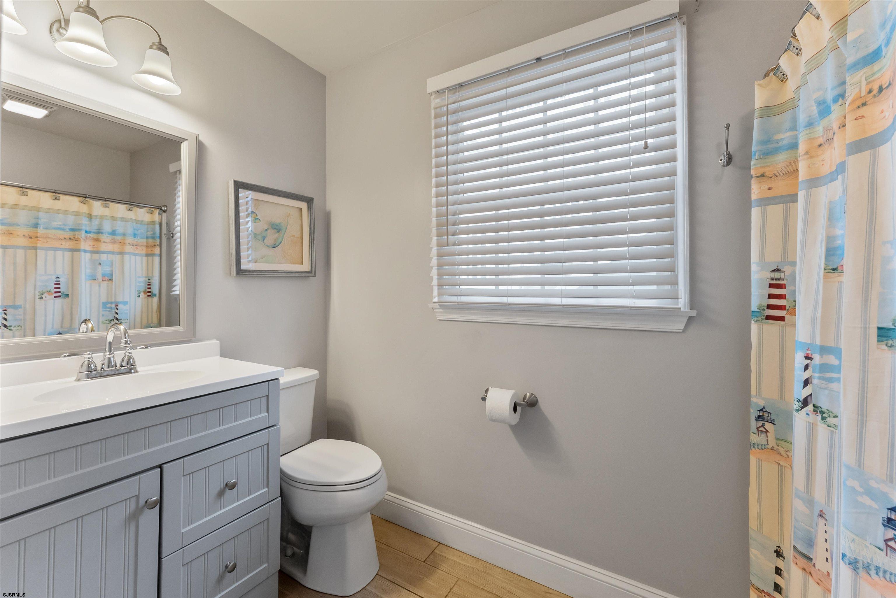 4930 Asbury Avenue, Unit 2 Ocean City, NJ 08226 - Photo 15 of 25 a bathroom with a toilet a sink a vanity and mirror