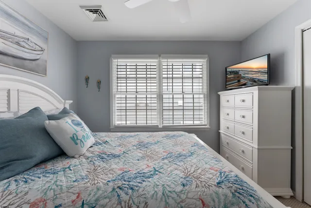 a bedroom with a bed and a flat tv screen on dresser