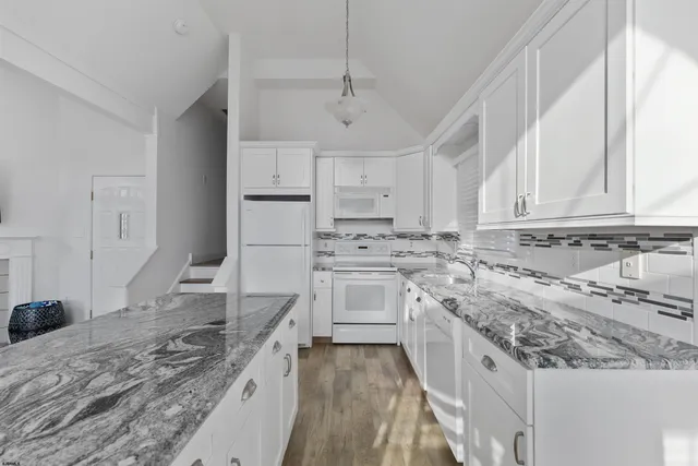 a living room with granite countertop kitchen island stainless steel appliances furniture a chandelier a large window and a sink