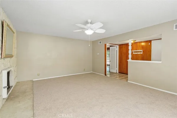 an empty room with a chandelier fan and windows