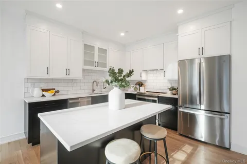 a kitchen with stainless steel appliances a white refrigerator a sink a stove a dining table and chairs