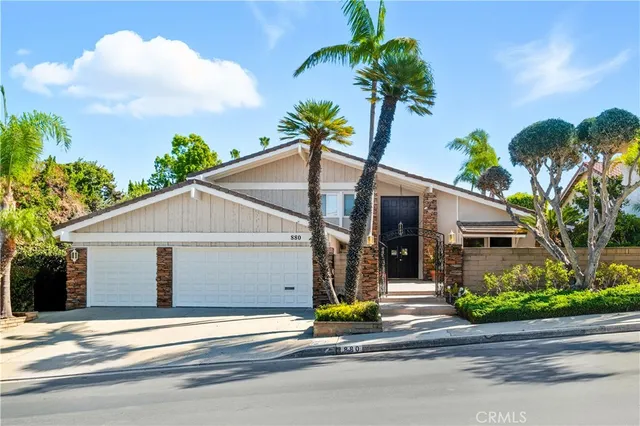 front view of a house with potted plants and a bench