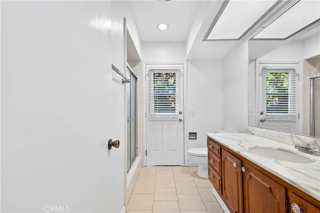 a bathroom with a granite countertop sink a toilet a mirror and shower