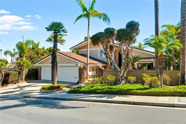a view of a house with a yard and palm trees