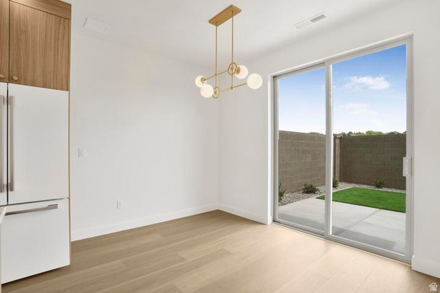 990 Manen Street Washington, UT 84780 - Photo 9 of 43 Open concept space featuring light wood-finish flooring, a contemporary gold-tone chandelier, and a built-in refrigerator with wood-paneled cabinetry