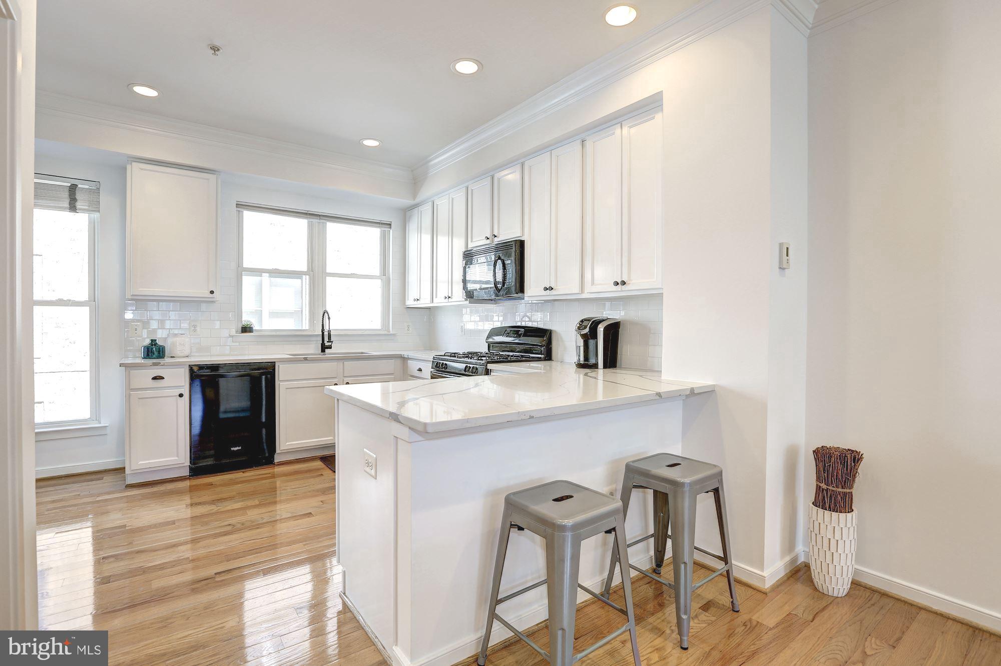 410 L Street Southeast Washington, DC 20003 - Photo 7 of 35 a kitchen with stainless steel appliances granite countertop a sink a stove a refrigerator cabinets and a dining table with wooden floor