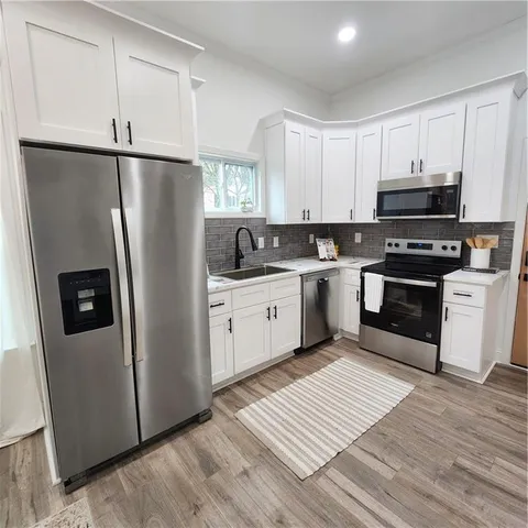 a kitchen with white cabinets sink and stainless steel appliances