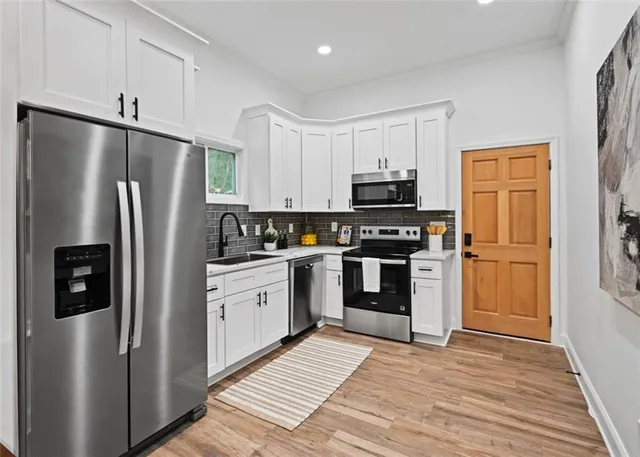 a kitchen with stainless steel appliances a refrigerator stove and white cabinets