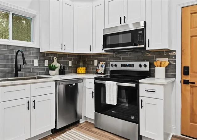 a kitchen with stainless steel appliances granite countertop a stove a microwave and a white cabinets